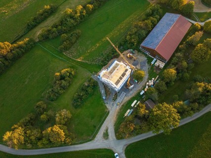 Aerial view of a construction site with a building under construction and solar roof in green