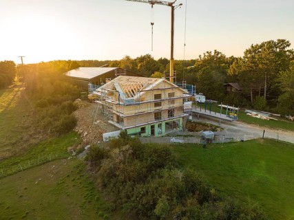 Building under construction at sunset, surrounded by nature in a rural location, timber house