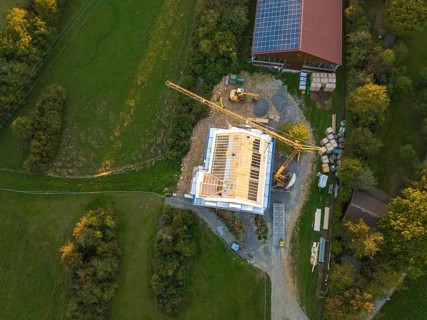 Aerial view of a construction site with a large construction building and solar system next door,