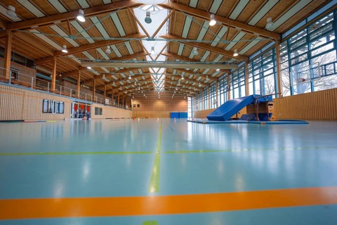 Modern sports hall with wooden roof, bright floor and large climbing frame, Schlehengäu sports hall