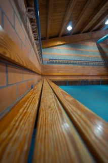 Long wooden bench on a brick wall with ceiling lights, Schlehengäu Sporthalle Gechingen, Calw