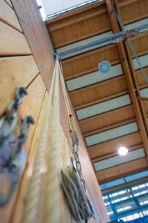 Climbing rope attached to a sports hall with wooden walls and neon lights, Schlehengäu Sporthalle