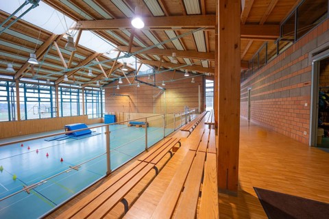Interior view of a gym with wooden benches and large windows, Schlehengäu Sporthalle Gechingen,