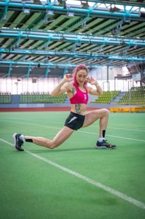 Woman stretching on green field, demonstrating flexibility and athletic energy, middle distance