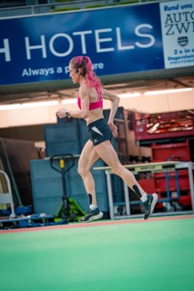 Female athlete dynamically running sideways through the interior of a hall, middle distance runner