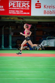 Female athlete sprints quickly through a hall, the movements are dynamic, middle distance runner