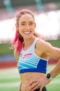 Woman smiling friendly with a wristwatch on in the stadium, middle distance runner Katharina