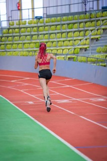 Female athlete concentrated while running, career lines in focus, middle distance runner Katharina