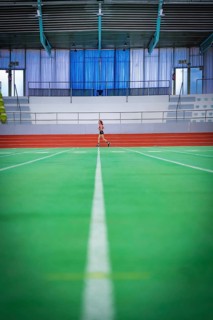 Wide-angle view of an empty track with a person running in the background, middle distance runner
