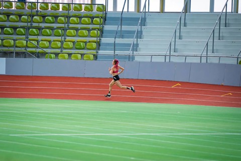 Woman running resolutely on a red indoor track, middle distance runner Katharina Jaiser,