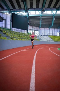 Woman running on a red indoor track in a stadium, middle distance runner Katharina Jaiser,
