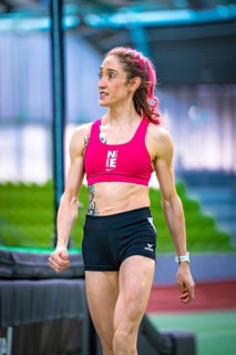 Woman wearing sporty clothes indoors showing determination against green background, middle