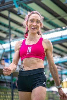 Sporty dressed woman with a smile indoors showing fitness and energy, middle distance runner