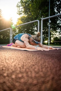 Woman in yoga pose on mat at sunset, natural environment, emphasizing peace and relaxation, middle