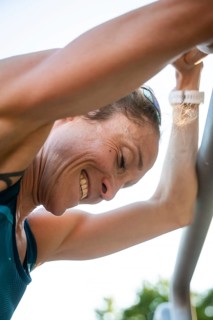 Woman practicing outdoors, smiling hard under sunlight during training, middle distance runner
