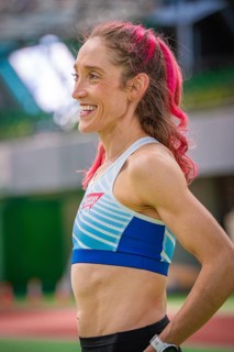 Smiling sportswoman with pink hair in stadium, looks fit and friendly, middle distance runner