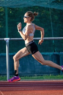 Female athlete moving on a running track, wearing sunglasses and athletic clothing, showing
