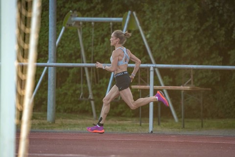 Woman runs intensively and concentrated along the track, middle distance runner Katharina Jaiser,