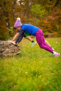 Two people doing outdoor sports exercises on rocks in autumn terrain, middle distance runner