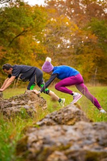 Man and woman training over rocks in an autumn park, middle distance runner Katharina Jaiser,