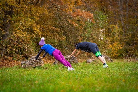 Two people working out outdoors doing push-ups on rocks in an autumn forest, middle distance runner
