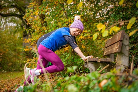 Woman stretching on a bench in an autumnal park, middle distance runner Katharina Jaiser,