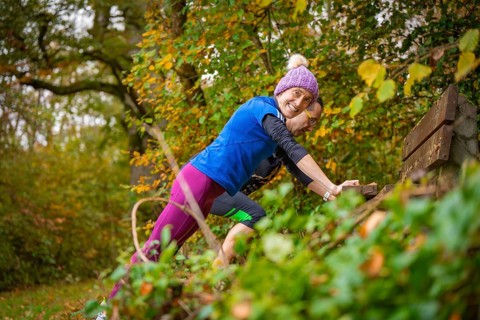 Woman wearing colorful sportswear smiles during a workout in autumn forest, middle distance runner