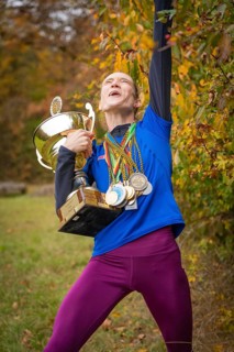 Woman with cup and medals cheers wildly in autumn, middle distance runner Katharina Jaiser,