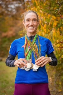 Woman proudly showing her medals in an autumnal setting, middle distance runner Katharina Jaiser,