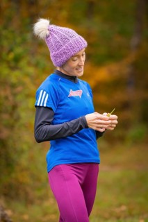 Woman wearing purple cap standing in autumn and looking at something, middle distance runner