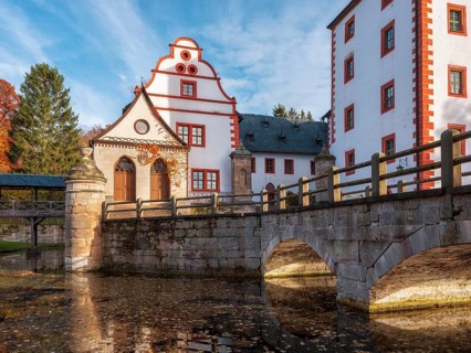 Kochberg Castle in autumn with bridge and reflection, colorful leaves in the castle moat,