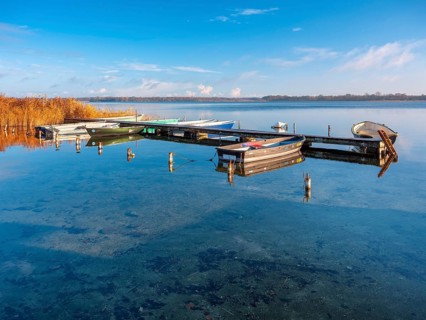 Jetty with rowing boats at Schaalsee in morning light, reeds in autumn colors, Schaalsee Biosphere