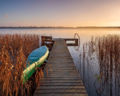 Jetty and inverted boat at Schaalsee in the first morning light, reeds in autumn colors, Schaalsee