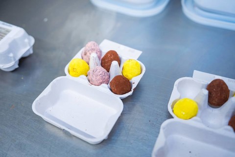 Different colored chocolate eggs in an egg carton on a metal surface, chocolate quail eggs, Easter