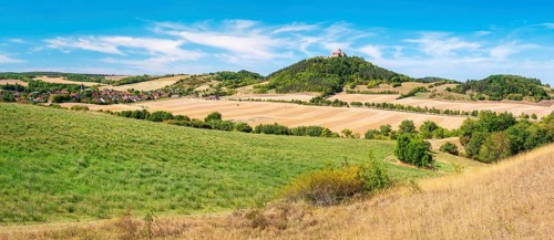 View over hilly landscape with meadows, fields and forests of Wachsenburg Castle and the village of