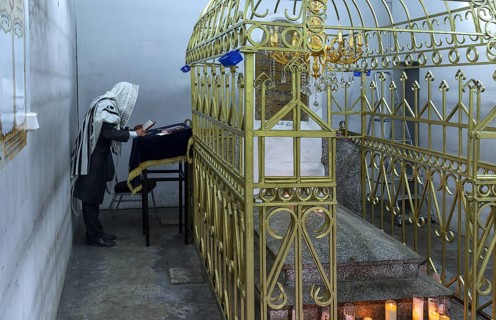 Orthodox Jew praying at the grave of Hasidic Rabbi Elimelech in Lezajsk Jewish Cemetery, Poland
