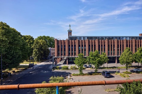 Rheinhallen exhibition halls, brick buildings, aboveground district heating pipeline, parking lot