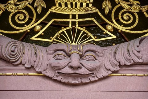 A stone face surrounded by ornaments and decorations, detailed view of the main portal of the