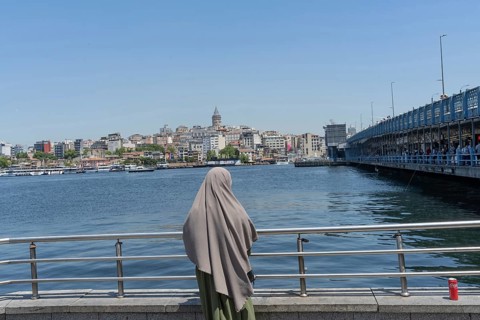 Istanbul, Turkey. June 23rd 2025. A Muslim women looks out across the Golden Horn towards the