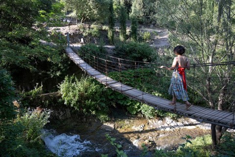 Tbilisi, Georgia. July 13th 2025. A foreign tourist crosses a wooden rope bridge inside the