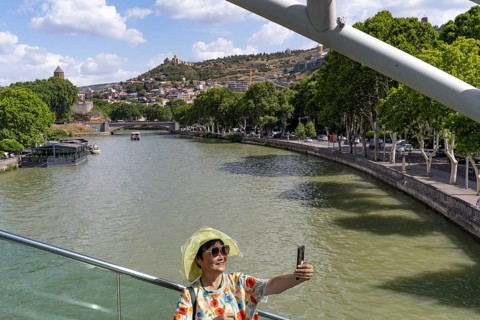 Tbilisi, Georgia. July 7th 2025. An Asian tourist poses for a photograph on the Bridge of Peace