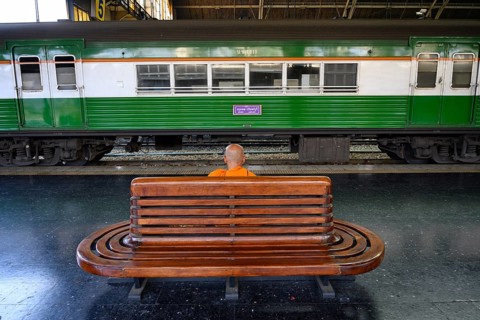 A Buddhist monks waits for his train on the platform at Hua Lamphong Railway Station, Bangkok,