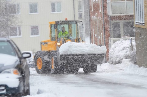 Loader clearing snow from snow-covered cars on streets in Ystad, Skåne County, Sweden, Scandinavia