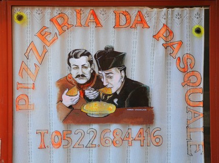Italy, village of Brescello, advertisement for Pizzeria Pasquale, with a picture of Don Camillo and