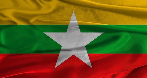 Flag of Myanmar with fabric textured background. Close up of National flag of Myanmar with