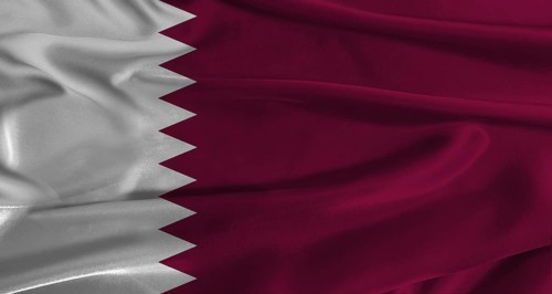 Flag of Qatar with fabric textured background. Close up of National flag of Qatar with realistic