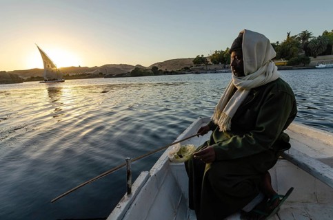 Aswan, Egypt. January 11th 2013 Local Nubian man fishing in the Nile with a Felucca sail boat at