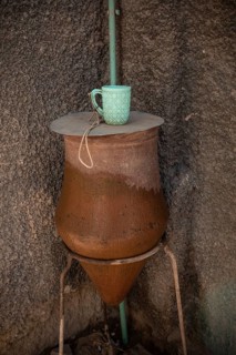 A local clay public clean water drinking fountain with plastic mug, along the Nile River in Upper