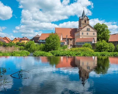 View across the Werra river to the small village of Themar with church and half-timbered houses,