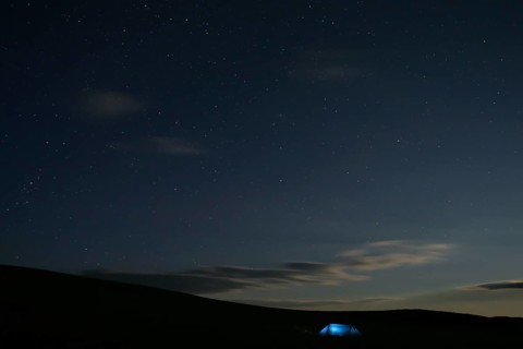 Illuminated tent stands alone in Mongolian steppe under starry sky at night, Nömrög National Park,